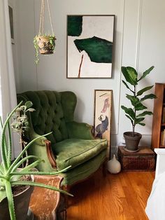 a living room with a green couch and potted plants on the wall next to it