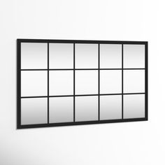 a black framed mirror hanging on the wall next to a white wall with multiple panes