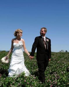 a bride and groom holding hands in a field full of purple flowers on their wedding day