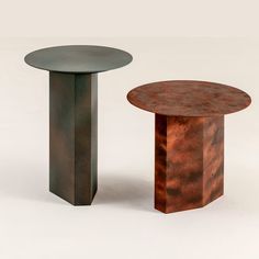 two round tables made out of metal and copper colored wood, each with a unique pattered surface