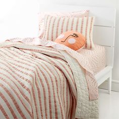 a bed with pink and white striped bedspread, pillows and pillowcases