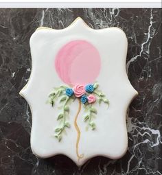 a decorated cookie with flowers and a balloon on it's side, sitting on a marble surface