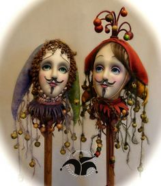 two dolls are standing next to each other on wooden sticks with beads hanging from them