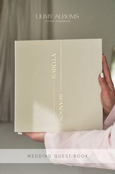 a person holding a wedding guest book in their hand