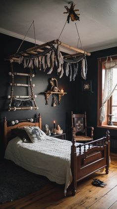 a bedroom with black walls and wood floors has an old fashioned bed frame that is adorned with feathers hanging from the ceiling