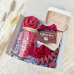 an open box with some items in it and a rose next to it on a table