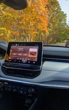 the dashboard of a car with an electronic device in it's center console and trees in the background