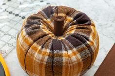 an orange and brown plaid pumpkin sitting on top of a table next to a pair of scissors