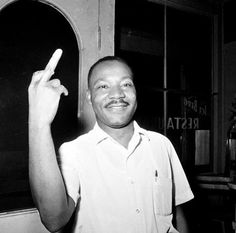 a black and white photo of a man pointing at something in the air with his finger