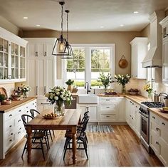 a kitchen filled with lots of white cabinets and counter top next to a wooden table