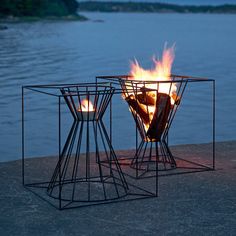 two fire pits sitting next to each other near the water