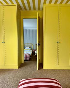 a bedroom with yellow painted walls and striped rugs on the floor, along with built - in closets