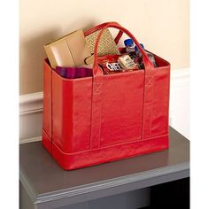 a large red bag sitting on top of a table next to a shelf with books and other items in it