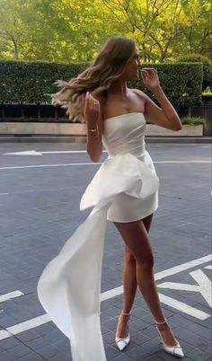 a woman in a white dress is walking down the street