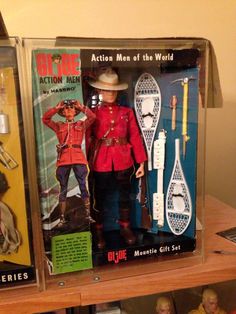 action man of the world toy set in display case on wooden shelf with other toys