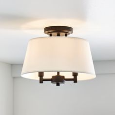 a light fixture with a white shade hanging from it's ceiling in a room