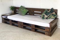 a bed made out of wooden pallets with two pillows on the top and bottom