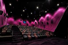 an empty theater with rows of seats and purple walls