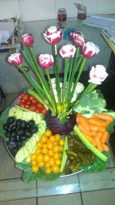 a platter filled with lots of different types of fruits and vegetables on top of a table