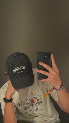 a man taking a selfie in front of his cell phone wearing a baseball cap