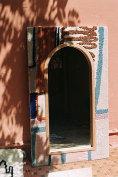 a mirror sitting on the side of a wall next to a plant and potted tree