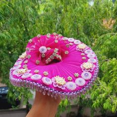 a hand holding a pink hat with flowers on it and other decorations around the top