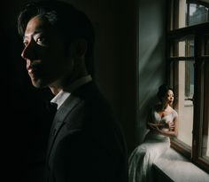 a man and woman standing in front of a window