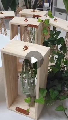 three wooden crates with plants in them sitting on a table next to other vases