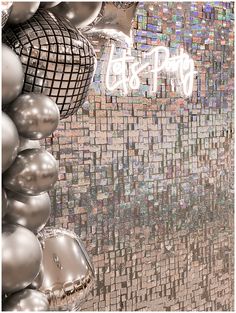 silver balloons and disco balls in front of a mosaic wall