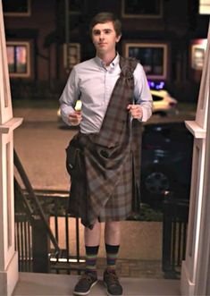 a man wearing a kilt is standing on the steps with his hands in his pockets