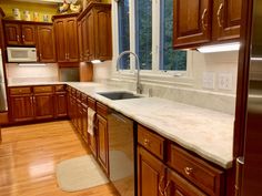 a kitchen with wooden cabinets and marble counter tops, along with hardwood flooring that matches the walls