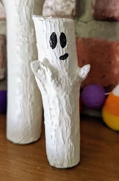 two white vases sitting on top of a wooden table with faces painted on them