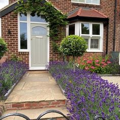 a house with purple flowers in front of it and an iron gate leading to the door