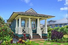 a small green and white house surrounded by flowers