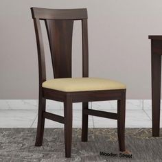 a wooden chair with a seat and back rest next to a small table in a room