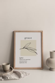 a framed print with the word grace on it next to a cup and saucer