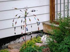 a wind chime sitting in the middle of a garden next to a white house