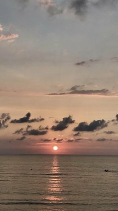 the sun is setting over the ocean with clouds