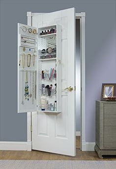 an open door to a closet with jewelry hanging on the wall and a mirror above it