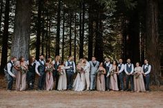 a group of people standing next to each other in front of some tall pine trees