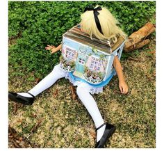 a doll sitting in the grass with a box on it's head and legs