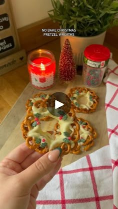 a person is holding a cookie in front of some christmas decorations and candles on a table