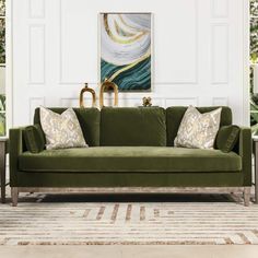 a green couch sitting in front of a painting on the wall next to a table