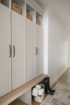 a room with white cupboards and flowers on the floor next to a rug in front of it