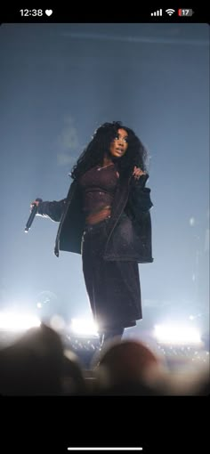 a woman standing on top of a stage in front of a crowd holding a microphone