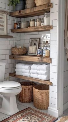 a white toilet sitting next to a wooden shelf filled with towels