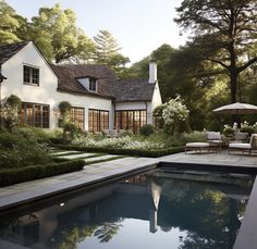 a pool in front of a house surrounded by trees