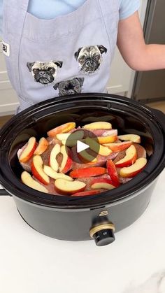 a person holding an open crock pot filled with sliced apples