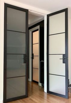 two black and white doors are open on the inside of a room with hard wood flooring