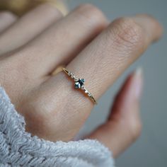 a woman's hand wearing a gold ring with two blue stones on the side